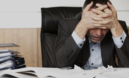 executive at desk feeling bad with hangover