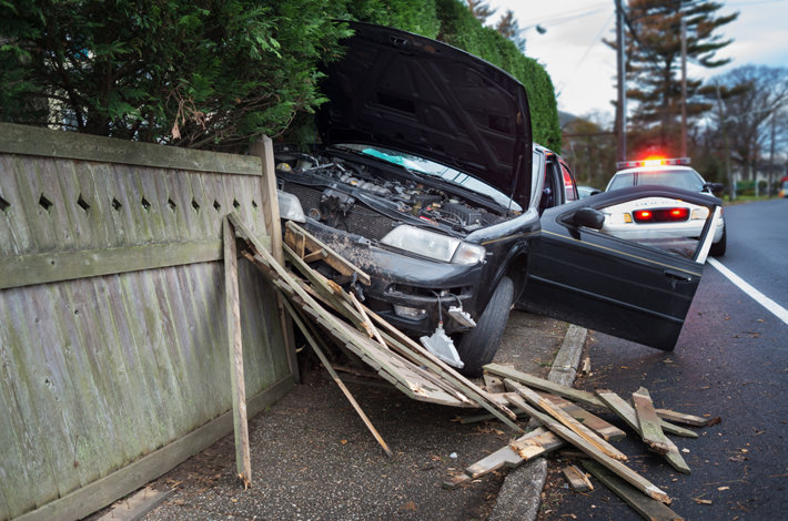 Wrecked car in a wooden fence