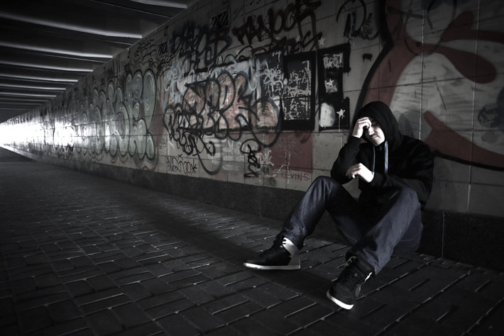 Drug addict sitting on the street of urban.