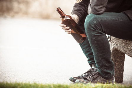 man sitting on bench with a bottle of alcohol
