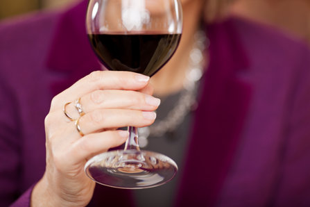 A mature woman holds a glass of wine. 