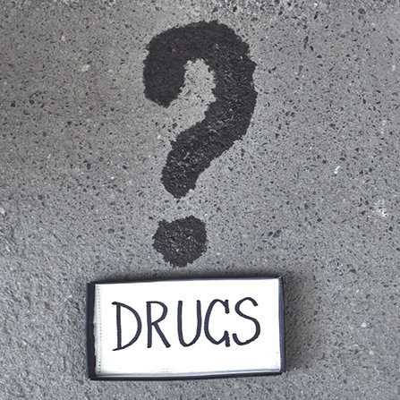 Whet question mark on the asphalt with Drugs sign 
