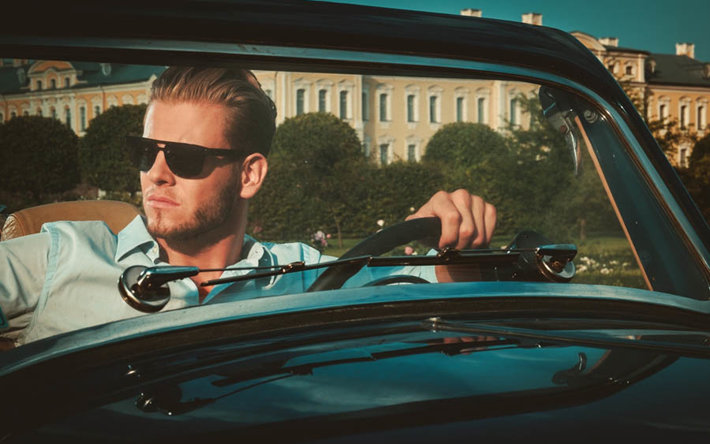 wealthy young man in car in front of mansion